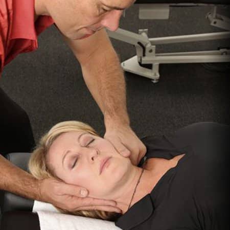 A professional Chiropractor performing neck adjustment on a female client to help her with neck mobility and joint health.