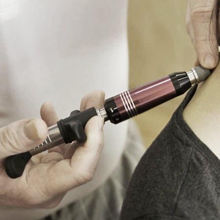 A professional chiropractor using a chiropractic activator on the neck of a patient to help them take care of their neck.