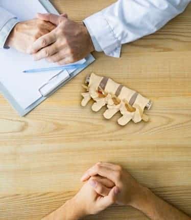 Chiropractor with anatomical model on desk