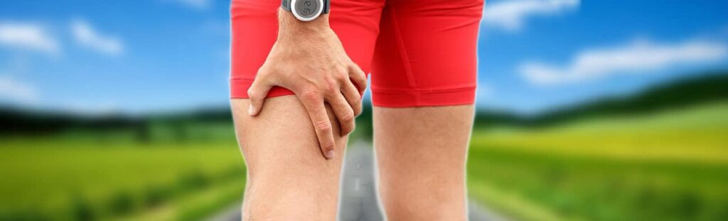 man with sciatica and leg pain holding back of thigh in pain
