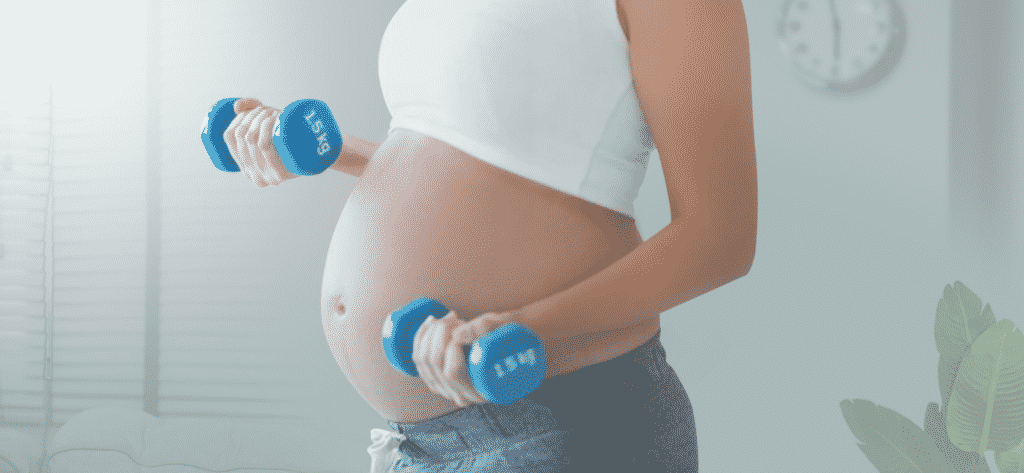 Pregnant women exercising while holding dumb bell